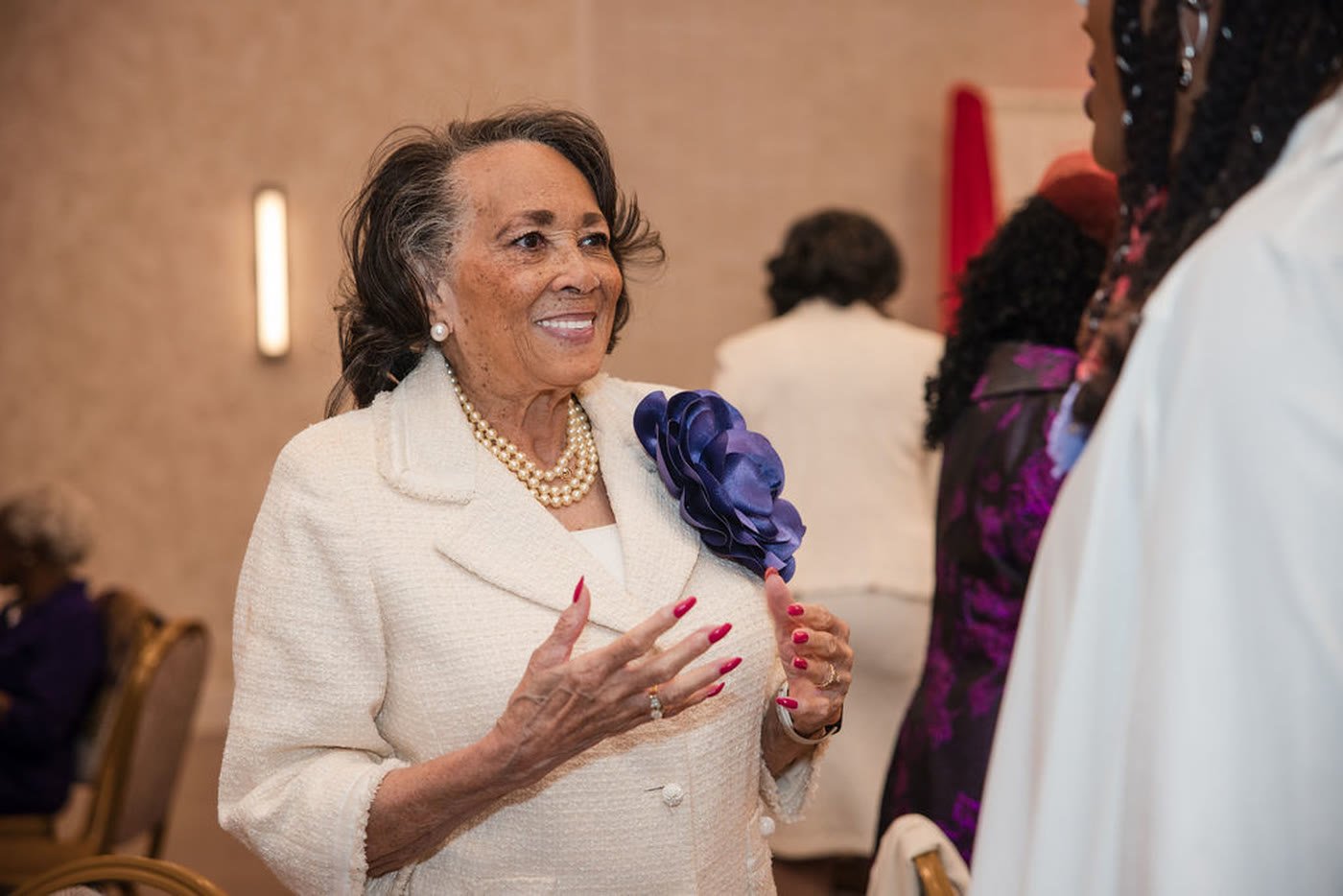 A guest in cream and pearls smiling across a banquet table